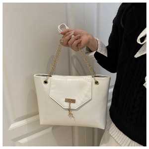 Close-up of white leather shoulder bag with gold chain strap and a small deer charm