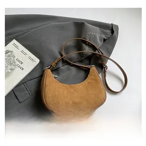 Detail of brown suede crescent bag texture with silver buckle on grey fabric