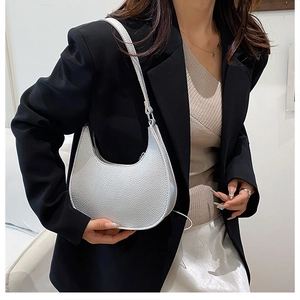 Detailed texture of silver crescent shoulder bag with lychee grain on a fashion model