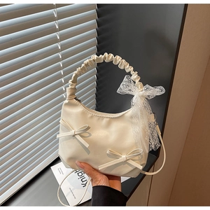 Vue détaillée du sac plissé crème avec des nœuds en dentelle et texture en cuir mat
