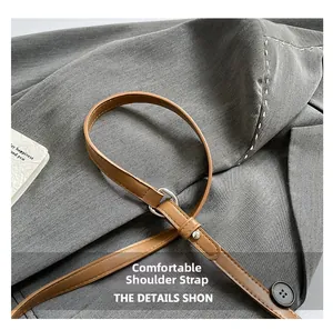 Detail showing the brown leather shoulder strap with a silver metal adjustment buckle