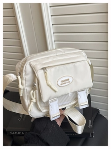 Detail of cream white nylon messenger bag showing multi-pocket design and secure buckles