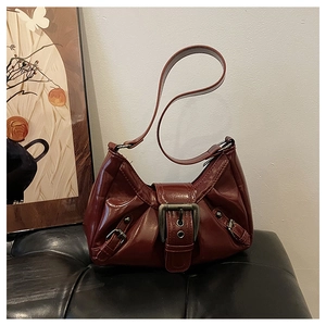 Close-up of vintage dark red leather shoulder bag with large metal buckle and rivets