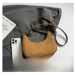 Macro detail of caramel suede crescent bag with leather trim and gold hardware