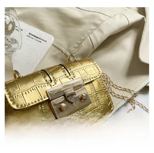 Dettaglio mini borsa a catena dorata con motivo coccodrillo e chiusura in metallo