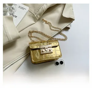 Macro view of golden crocodile embossed leather crossbody bag with metallic chain strap