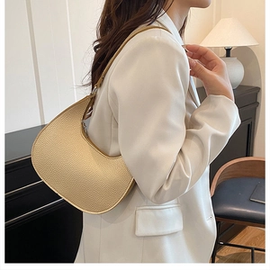 Detail view of champagne crescent bag with lychee grain leather on a model's shoulder
