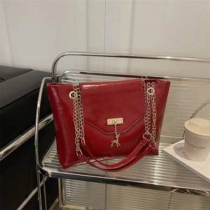 Sac à bandoulière en cuir rouge brillant avec chaîne dorée et pendentif cerf sur grille