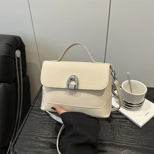 Sac bandoulière beige minimaliste avec texture tressée et fermoir en fer à cheval argenté