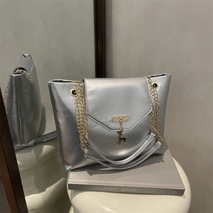 Sac cabas argenté métallisé avec chaîne dorée et pendentif cerf sur socle blanc