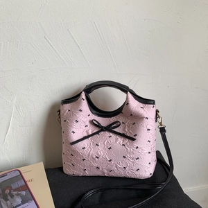 Pink bow shoulder bag with pleated texture and black handle in a minimalist setting