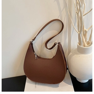 Detail of brown crescent bag showing high-quality lychee texture leather and silver zipper