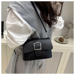 Detail shot of a vintage black crossbody bag with large silver metal buckle on a model