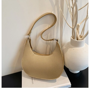 Detailed side view of golden crescent shoulder bag with lychee grain leather texture