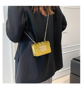 Detail of golden crocodile embossed leather crossbody bag with metal chain strap