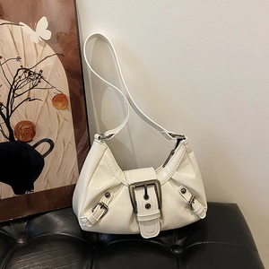 Large cream patent leather shoulder bag with vintage silver buckle details on a black stool