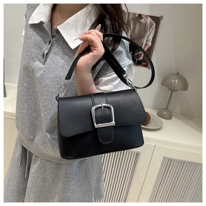 Detail of a minimalist black square bag with a prominent silver metal belt buckle closure