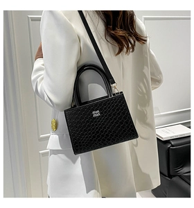 Detailed view of black woven texture leather handbag with stylish metal strap connectors