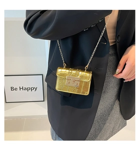 Dettaglio mini borsa a tracolla dorata con motivo coccodrillo e catena in metallo