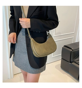 Detail of army green suede crescent bag shown with adjustable strap on leather sofa