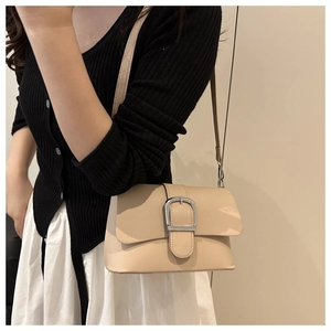 Detail of minimalist beige leather crossbody bag with a large silver buckle closure