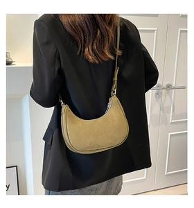 Model wearing a grass green suede crescent shoulder bag with adjustable strap and metal zipper