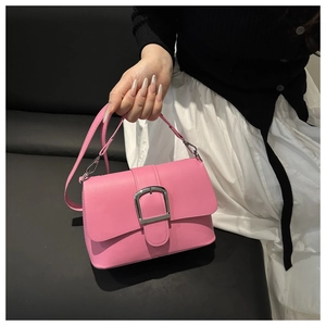 Detailed view of a pink crossbody bag with a large silver buckle held by a model