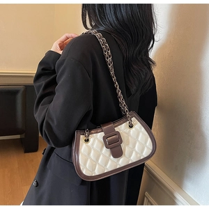 Detail of retro quilted crossbody bag featuring cream PU leather with brown trim and chain strap