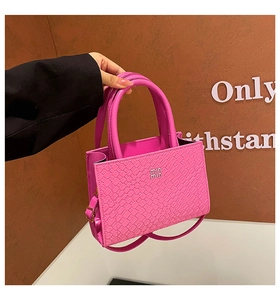 Macro detail of bright pink woven texture bag with metallic branding and dual handles