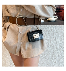 Detail of a black crocodile pattern mini square bag with a gold metal clasp and chain