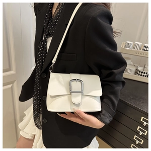Close-up of a white rectangular crossbody bag with a large silver buckle on a model