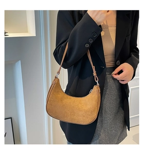 Detail of a brown suede crescent hobo bag with sleek leather strap and silver zipper