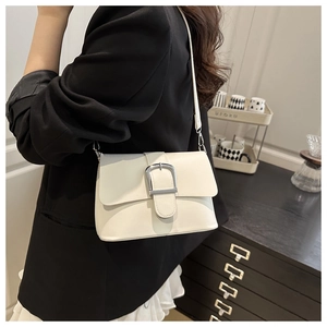 Close-up of a white leather crossbody bag with a large silver U-shaped metal buckle