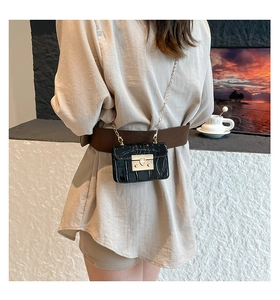 Detail of black crocodile texture mini chain bag with gold metal buckle on model waist
