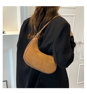 Brown suede crescent bag shown on shoulder of model for size and style reference