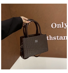 Detail of dark brown woven texture tote bag with circular handles and min min logo