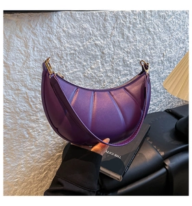 Close-up of dark purple crescent bag with vertical pleated texture and golden zipper