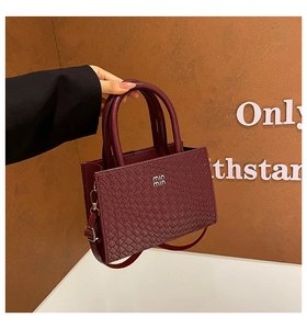 Close-up of burgundy woven texture and metal buckle detail on retro crossbody bag