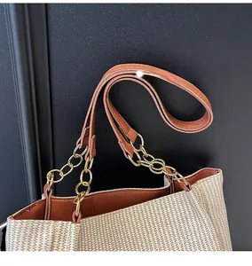 Detail of woven tote bag featuring beige texture with brown straps and gold chain links