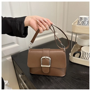 Detail of a brown leather shoulder bag with a stylish silver buckle and matte finish