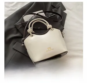 Detailed view of bicolor bucket handbag with gold-stamped logo and knotted handle