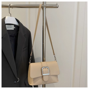 Close-up of beige PU leather bag with large silver square buckle and adjustable strap