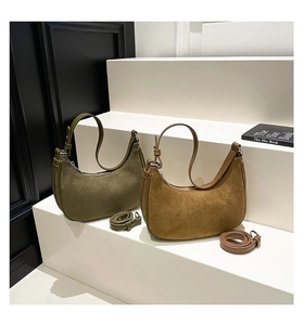 Detail of two suede crescent bags in olive and earth tones with leather stitching