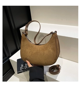 Detail of brown suede crescent bag with silver zipper and slim detachable shoulder strap