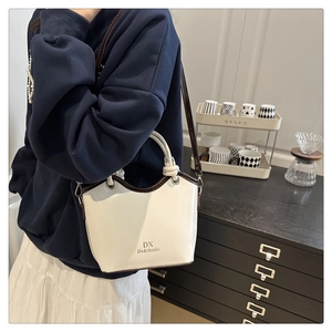 Detail of minimalist bucket bag showing cream leather texture and contrast brown piping trim