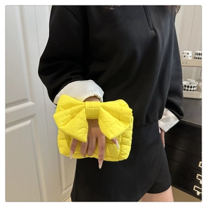 Close-up of bright yellow quilted cloud bag with large bow detail and ripple texture
