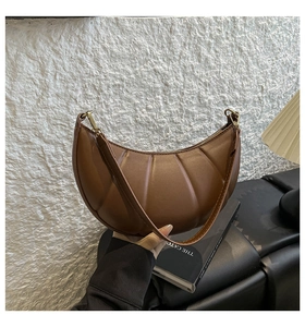 Detail shot of brown croissant bag featuring vertical pleated texture and zipper closure