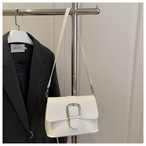 Detail of cream flap crossbody bag with square silver buckle and textured leather finish