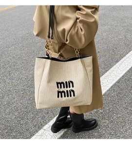 Detail of woven tote bag with chain strap and printed lettering in urban street style