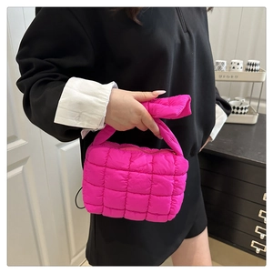 Dettaglio macro della borsa trapuntata magenta con trama in nylon lucido e imbottitura